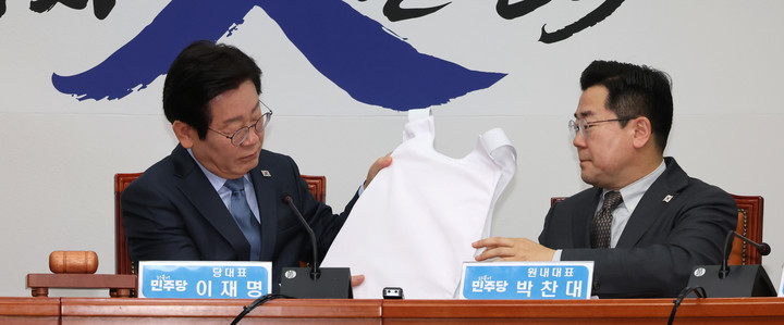 22일 서울 여의도 국회에서 열린 최고위원회의에서 (왼쪽) 이재명 더불어민주당 대표가 방검복을 살펴보고 있다.
